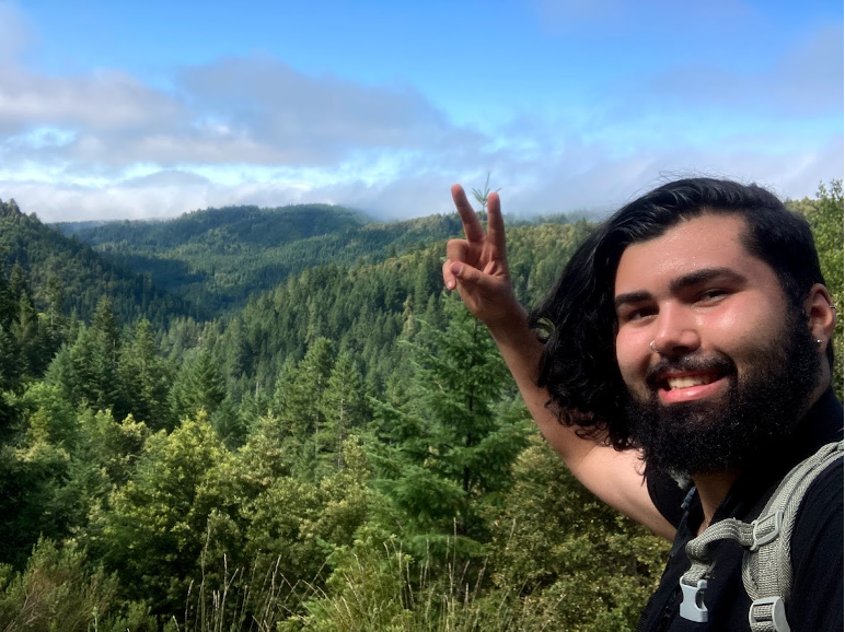 Jordan Stevens gives a peace sign in front of a forest